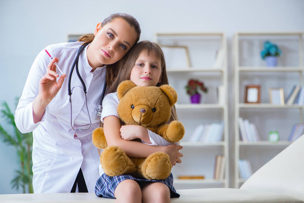 vrouw vrouwelijke arts onderzoeken klein schattig meisje met speelgoed beer - Foto, afbeelding