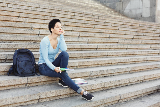 Jeune fille étudiante réfléchie prenant des notes dans un carnet
 - Photo, image