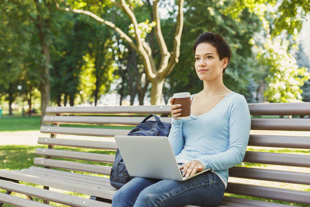 Mujer joven usando el ordenador portátil en el parque, espacio de copia
 - Foto, Imagen