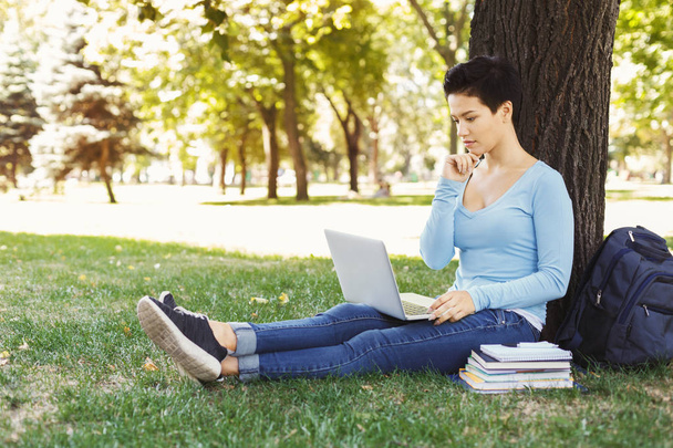 Woman sitting on the grass with laptop outdoors - Foto, imagen