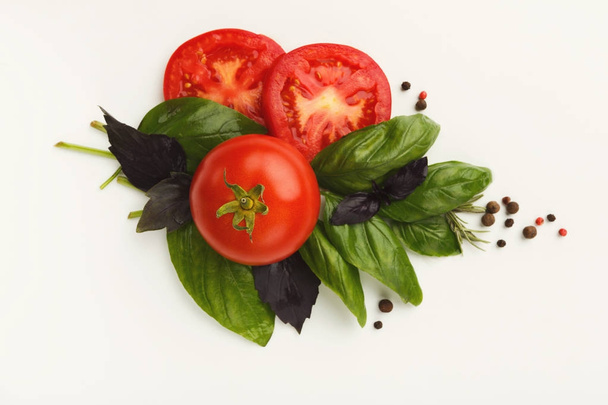 Κόκκινες ντομάτες και φύλλα βασιλικού που απομονώνονται σε λευκό - Φωτογραφία, εικόνα