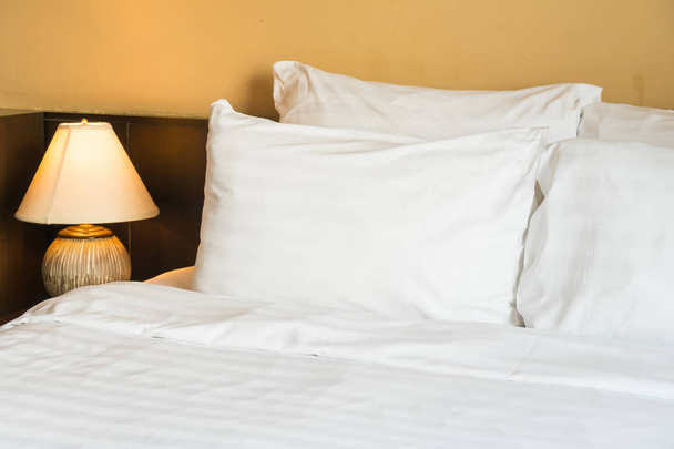 Oreiller confortable blanc sur lit avec lampe de lumière décoration intérieure de la chambre - Photo, image