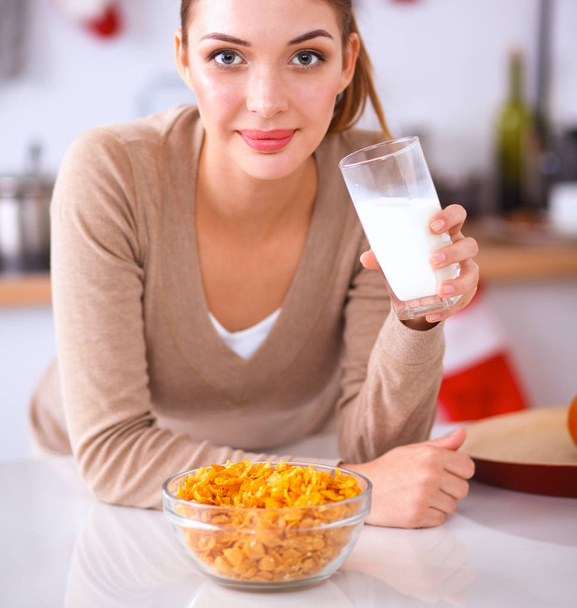 Smiling attractive woman having breakfast in kitchen interior - Foto, imagen