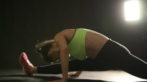 Young attractive woman in studio stretching legs and abdominal - Filmmaterial, Video