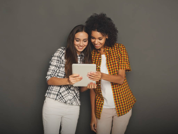 Дві щасливі друзі-жінки використовують цифровий планшет
. - Фото, зображення
