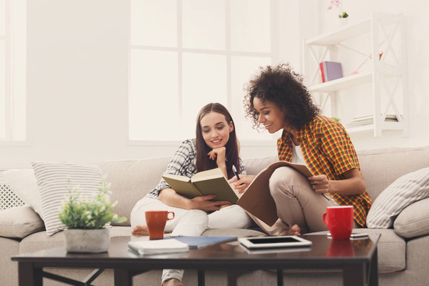Two female friends reading books at home - Foto, Bild