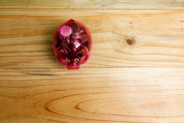 Hucha roja y tarro de monedas en la mesa de madera. Concepto de ahorro e inversión
. - Foto, Imagen