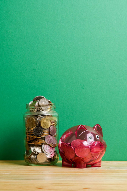 貯金箱赤と緑の背景に硬貨の瓶。節約と投資の概念. - 写真・画像