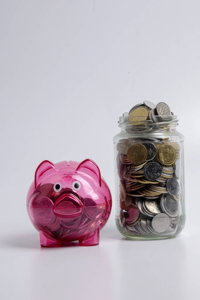 Rode piggy bank en kruik van munten op witte achtergrond. Opslaan en investeringen concept. - Foto, afbeelding