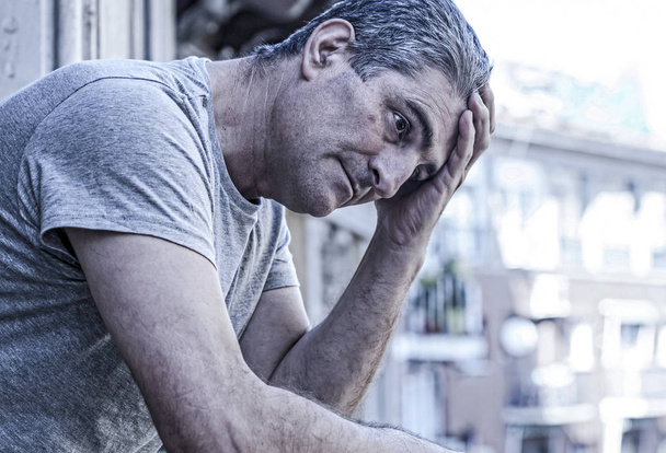 Trauriger und depressiver Mann in den Vierzigern schaut zu Hause durch die Fenster - Foto, Bild