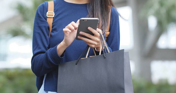 Mulher usando telefone celular e detém sacos de compras
 - Foto, Imagem