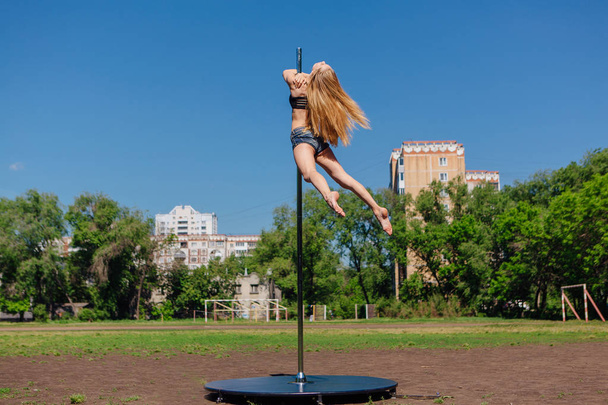 Fit attractive girl dancing near portable pole at summer day - Фото, изображение