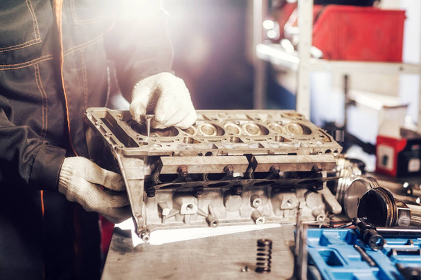 the mechanic installs a new valve. Disassemble engine block vehicle. Motor capital repair. Sixteen valves and four cylinder. Car service concept. - Zdjęcie, obraz