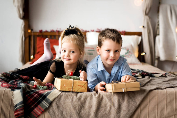 Κορίτσι και αγόρι ανοίγουν δώρα. Καλά Χριστούγεννα και καλές γιορτές. - Φωτογραφία, εικόνα