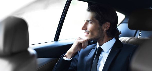 successful man sitting in the back seat of a car - Foto, afbeelding
