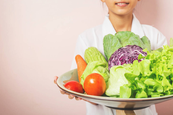Διατροφολόγος στέκεται κρατώντας ένα δίσκο με υγιή λαχανικά συνιστάται στους καταναλωτές. - Φωτογραφία, εικόνα