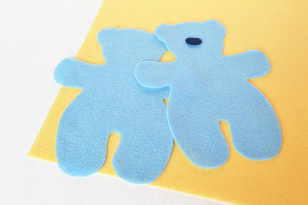 Set for making bear toy from felt. Sewing concept. Sew toys. Felt parts set. Handmade felt blue bear set on wooden yellow felt  - Photo, Image