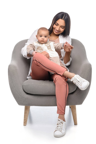smiling young mother resting on arm chair together with little baby isolated on white - Foto, afbeelding