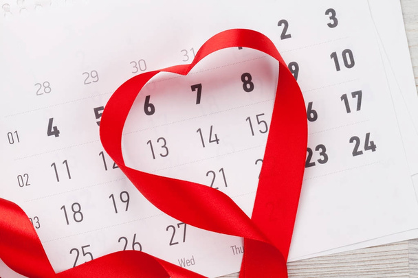 バレンタインの日グリーティング カード カレンダーと心形の木製の背景にリボン。トップ ビュー  - 写真・画像