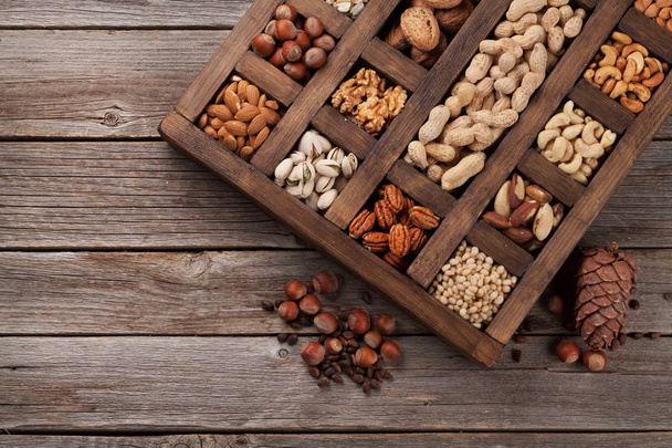Variada selección de frutos secos: cacahuetes, avellanas, castañas, nueces, pistachos y pacanas en caja de madera. Vista superior
 - Foto, Imagen
