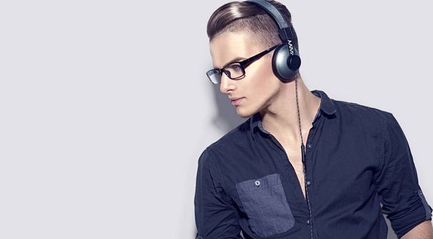young man enjoying music on headphones on gray background - Φωτογραφία, εικόνα