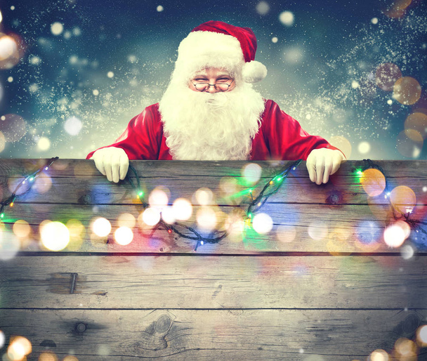 Happy Santa Claus holding wooden banner background - Foto, immagini