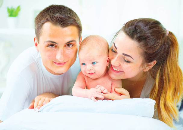 Familia joven feliz con bebé recién nacido sobre fondo blanco
 - Foto, imagen