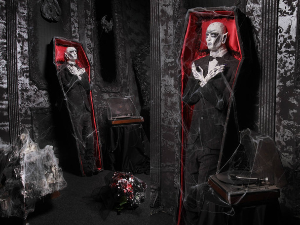 гроб с мертвой марионеткой человека, стоящего у стены в черной комнате с черной штукатуркой
 - Фото, изображение