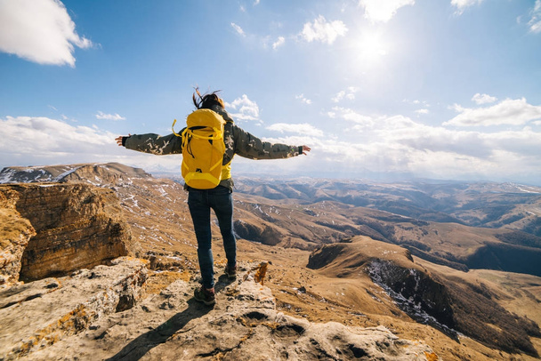 active young girl travels through the Caucasian mountains with a yellow backpack, enjoys the sun and nature - Foto, Bild