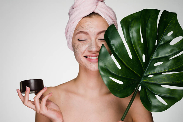 happy smiling girl with a pink towel on her head applied a coffee scrub on her face, day spa - Foto, Imagem