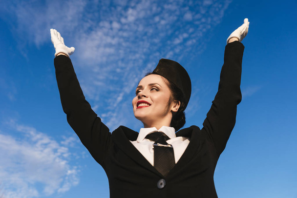 happy young woman stewardess in uniform likes flying, under blue sky - Foto, imagen