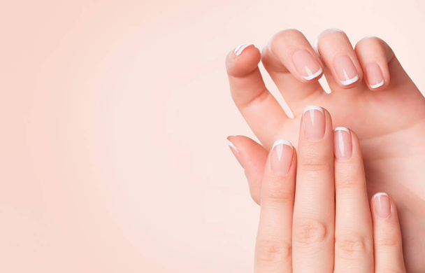 Female hands with french manicure on pink background - Zdjęcie, obraz