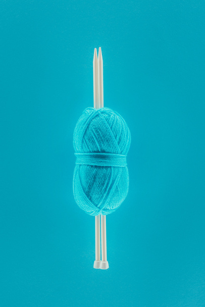 bovenaanzicht van blauw breien garens bal met breinaalden, geïsoleerd op blauw - Foto, afbeelding