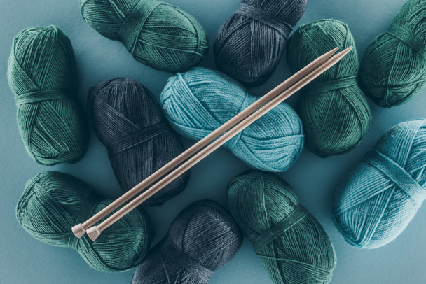 top view of blue and green knitting yarn with knitting needles, isolated on blue - Photo, Image