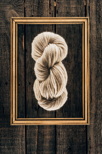 top view of white knitting yarn with frame on wooden background - Фото, зображення