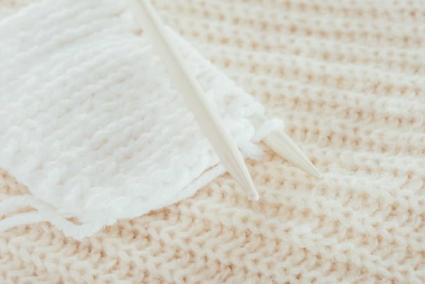 lähikuva neulepuikoista valkoisella villalangalla
 - Valokuva, kuva
