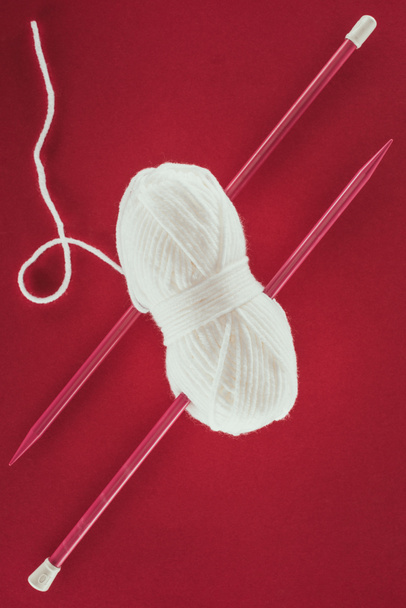 vue de dessus de boule de fil blanc et aiguilles à tricoter, isolé sur rouge
 - Photo, image