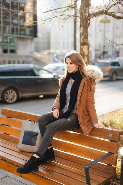 Young pretty girl sit on the bench. Hang her scarf in one hand a - Фото, зображення