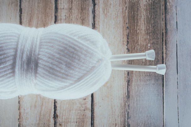 top view of white yarn and knitting needles on wooden background - Fotó, kép