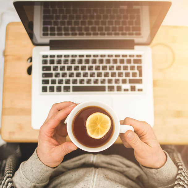 Felülnézet kezében a csésze tea citrommal és laptop - Fotó, kép
