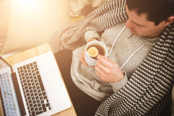 Young man laying in bad with laptop and cup of tea. - Foto, immagini