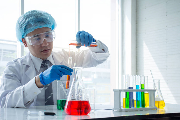 Nahaufnahme eines asiatischen Wissenschaftlers Chemiker Warteschlange mit einer roten flüssigen chemischen Lösung machen Test oder Forschung im Labor - Foto, Bild
