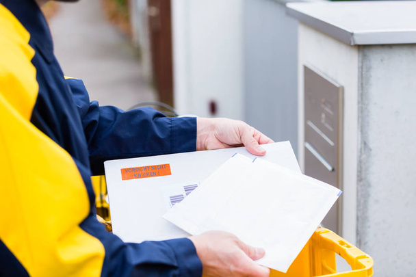 Carteiro entregando cartas para caixa de correio do destinatário
 - Foto, Imagem