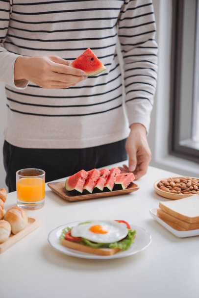 άνθρωπος τρώει πρωινό στο σπίτι, πρωί με σάντουιτς και φρούτα. - Φωτογραφία, εικόνα