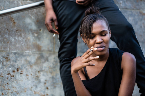 Jeune femme afro-américaine et l'homme fumant en plein air dans la ville
 - Photo, image
