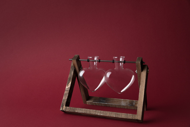 two empty heart shaped glass jars on wooden stand on red - Foto, Imagem
