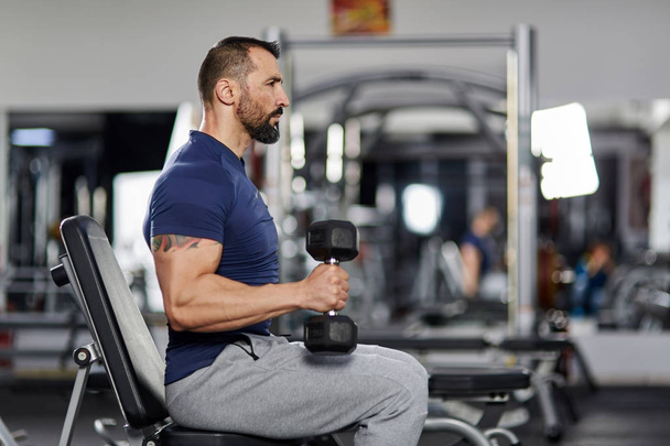 Man doing biceps curl with dumbbells in the gym - Fotó, kép