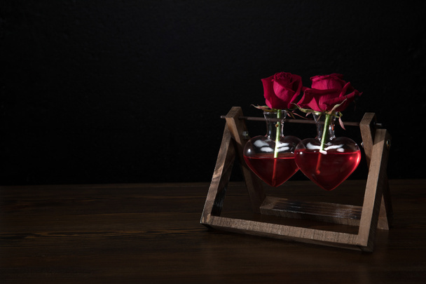 dos rosas rojas en jarrones en forma de corazón en soporte de madera
 - Foto, Imagen