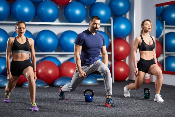 Fitness instructor and girls doing lunges in the gym - Foto, Bild