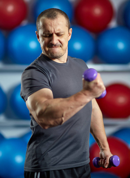 Funny image of a big strong man with very small dumbbells - Fotó, kép